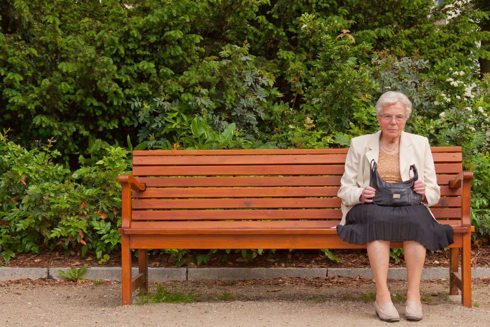 бабушка сидит на скамейке и машет ногами